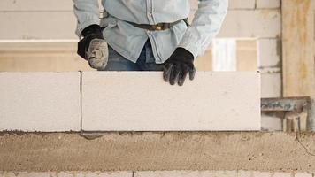 costruzione lavoratori siamo fabbricazione bianca leggero calcestruzzo blocchi quello siamo meglio di cemento mattoni, popolare nel il costruzione di le case e pubblico edifici. foto