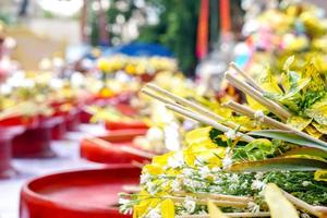 avvicinamento e colture mucchio di fragrante fiori con incenso su rosso di legno vassoi per culto il Budda nel il tailandese lanna dedicare un' mazzo di fiori per culto il Budda tradizione. foto