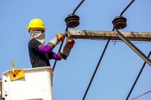 elettricisti Lavorando su cavo auto per riparazione il energia linea sotto leggero blu cielo sfondo. foto