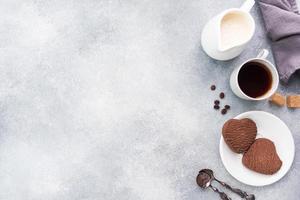 cioccolato cuore biscotti e un' tazza di nero caffè con latte su il tavolo, superiore Visualizza. copia spazio. foto