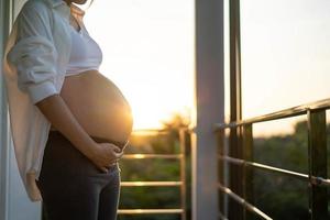 un 8 mese incinta donna delicatamente tocchi sua pancia a tramonto. mamma con bambino nel abbomeno così contento tempo mentre lei è incinta. foto