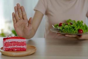 dieta concetto. donne rifiuto torta e mangiare insalata per bene Salute. foto