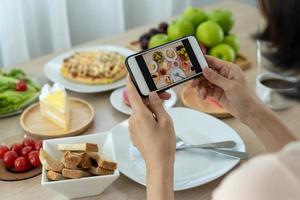 donne uso mobile telefoni per prendere immagini di cibo o prendere vivere video su sociale networking applicazioni. cibo per cena sembra appetitoso. fotografia e prendere immagine per revisione cibo concetti foto