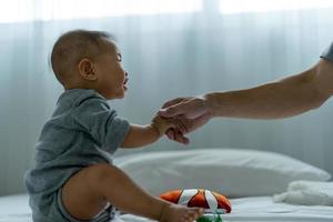 un asiatico bambino si fida il suo Il padre di mano per In piedi su. padre e figlio la spesa tempo insieme foto