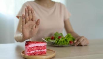 dieta concetto. donne rifiuto torta e mangiare insalata per bene Salute. foto