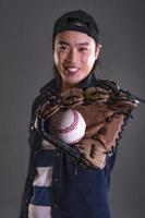 asiatico uomo giocando baseball. Tenere baseball e indossare baseball guanto. isolato su grigio sfondo foto