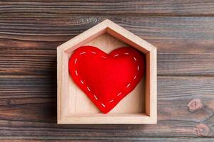 superiore Visualizza di rosso tessile cuore nel un' Casa su di legno sfondo. casa dolce casa concetto. San Valentino giorno foto
