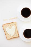 Sandwich per prima colazione nel modulo di cuore con formaggio - bene mattina cartello e Due caffè tazze foto