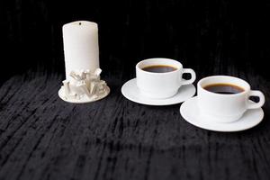 candela e Due tazze di caffè su un' nero sfondo foto