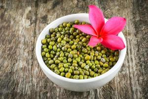 mung fagioli o verde fagioli seme cereale totale cereali nel bianca ciotola con frangipani fiore plumeria foto