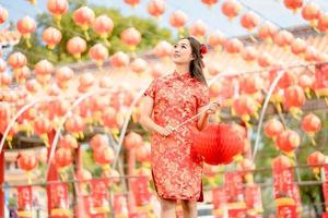 giovane signora donna indossare tradizionale cheongsam qipao costume Tenere lanterna nel Cinese buddista tempio. celebrare Cinese lunare nuovo anno, festivo stagione vacanza. emozione Sorridi foto