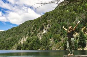 donna in piedi su il riva di un' lago sensazione gratuito. foto