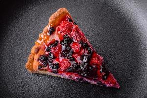 delizioso fresco torta con lamponi e altro frutti di bosco e formaggio su un' buio piatto foto