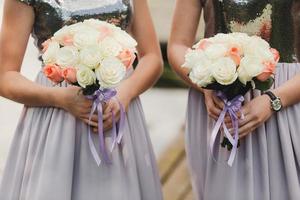 la sposa in un elegante abito da sposa tiene un bellissimo mazzo di fiori diversi e foglie verdi. tema del matrimonio foto