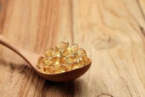 pesce olio capsule su di legno cucchiaio. foto