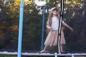 poco bambino ragazza salto su il trampolino nel il indietro cortile foto