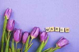 viola mazzo di fiori tulipani sfondo con con il parola marzo su veri peri sfondo. foto