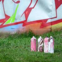 un' pochi Usato dipingere lattine menzogna su il terra vicino il parete con un' bellissimo graffiti la pittura. strada arte e vandalismo concetto foto