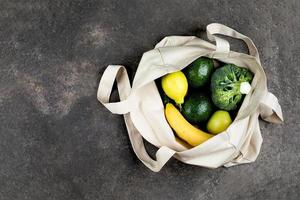 cotone shopping Borsa con verde verdure e giallo frutta. superiore Visualizza, piatto posizione, copia spazio. zero sciupare, eco amichevole concetto. foto