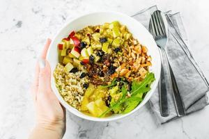 insalata pranzo ciotola nel donna di mano. cheto insalata nel ciotola su marmo sfondo. superiore Visualizza, vicino su. concetto di salutare cibo foto