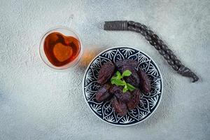 Ramadan cibo concetto. fresco date, roseto perline, tazza di tè su calcestruzzo sfondo. Ramadan kareem foto