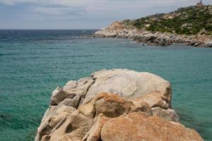 un' turchese blu mare e bianca sabbia spiaggia con rocce nel sardegna Italia foto