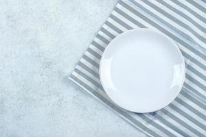 tavolo ambientazione indietro. bianca piatto su blu pietra tavolo con blu a strisce tovaglia e copia spazio foto