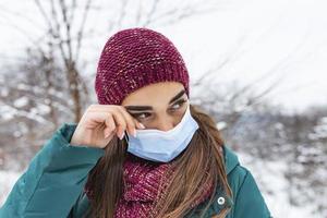 evitare toccante il tuo occhi. donna indossare viso maschera sfregamento sua occhio all'aperto. giovane donna toccante sua occhio con sporco mano. non fare toccare il tuo viso, fermare diffusione coronavirus foto