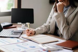 mano dell'uomo d'affari che lavora con il nuovo computer moderno e scrive sul diagramma di strategia del blocco note come luce del mattino di concetto foto