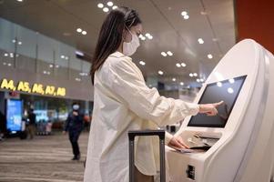 una donna viaggiatrice indossa una maschera protettiva nell'aeroporto internazionale, viaggia sotto la pandemia covid-19, viaggi di sicurezza, protocollo di allontanamento sociale, nuovo concetto di viaggio normale foto