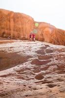 giovane caucasico ragazza donna scalata giù a partire dal roccia formazione viso sua paure nel natura nel wadi Rum deserto su vacanza vacanza deserto giro foto