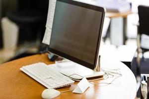 posto di lavoro con taccuino il computer portatile confortevole opera tavolo nel ufficio finestre e città Visualizza. foto