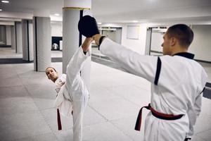 giovane taekwondo combattente con invalidità praticante alto calcio con sua allenatore nel Salute club. foto