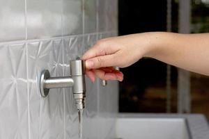 asiatico donna apertura rubinetto per lavare mani pulito prima e dopo toccante cibo. morbido e selettivo messa a fuoco. foto