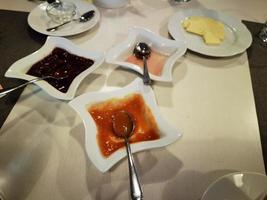 tavolo impostato per prima colazione con marmellata, fette biscottate e cappuccino, il tipico continentale prima colazione foto