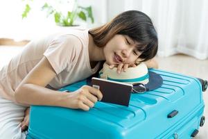 asiatico donne siamo seduta guardare a loro passaporti e sorridente felicemente. donna Imballaggio valigia per preparare per viaggio su vacanza.viaggio e preparare un' capi di abbigliamento Borsa concetto. foto