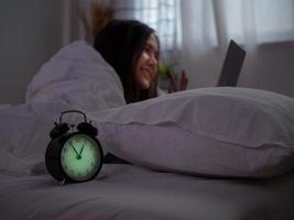 un asiatico donna è utilizzando un' smartphone per rendere video chiamate con sua fidanzato nel letto prima andando per letto a notte. smartphone dipendenza foto