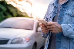 sicurezza di emergenza. l'uomo sta componendo un telefono cellulare per un numero di emergenza a causa di un guasto a un'auto nella foresta. la manutenzione dell'auto prima del viaggio aumenta la sicurezza dagli incidenti. foto