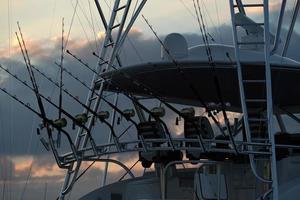 molti pesca asta su un' barca a tramonto foto