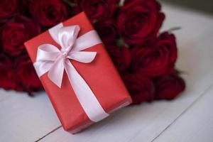 vicino su rosso regalo scatola con mazzo di roseo Rose sfocato sfondo. San Valentino giorno, nozze, compleanno e speciale occasione concetto. copia spazio per testo. foto