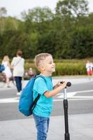 un' ragazzo su un' scooter lungo il argine di il città. viaggio. zaino su il Indietro. il viso esprime naturale gioioso emozioni. non messo in scena fotografie a partire dal vita