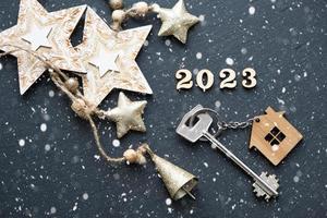 Casa chiave con portachiavi Villetta su nero sfondo con stelle, fiocchi di neve. contento nuovo anno 2023-di legno lettere, saluto carta. Acquista, costruzione, trasloco, mutuo foto