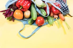 blu maglia shopping Borsa pieno di fresco azienda agricola verdure è dire bugie su superiore di giallo sfondo con copia spazio su parte inferiore. foto