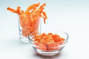 trasparente ciotola e bicchiere con fatti in casa salutare carota patatine fritte su dolce blu sfondo. foto