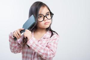 poco ragazza Asia pettinatura sua capelli, bianca sfondo foto