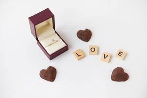 il iscrizione nel di legno lettere amore, piccolo tartufo dolci nel il modulo di un' cuore. diamante squillare scatola - matrimonio proposta. foto
