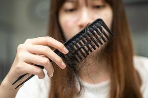 la donna asiatica ha problemi con la caduta dei capelli lunghi attaccata alla spazzola del pettine. foto