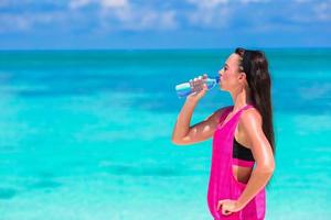 donna che beve acqua vicino all'oceano