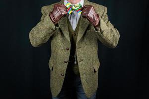 signore nel tweed completo da uomo e pelle guanti raddrizzatura arco cravatta su nero sfondo. concetto di classico e eccentrico Britannico signore foto