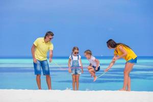 famiglia divertirsi con una corda per saltare in una spiaggia foto